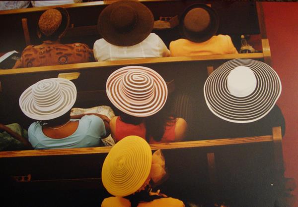 An overhead view of black womens' hats as they sit in church
